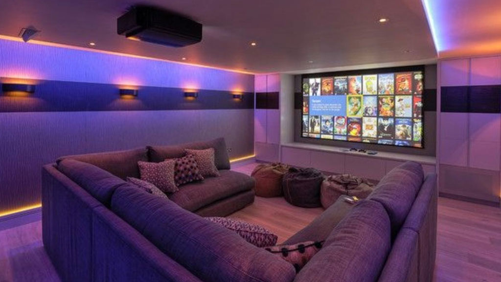 Sala de cine en casa con contraventanas cerradas filtrando luz exterior para mejor aislamiento acústico