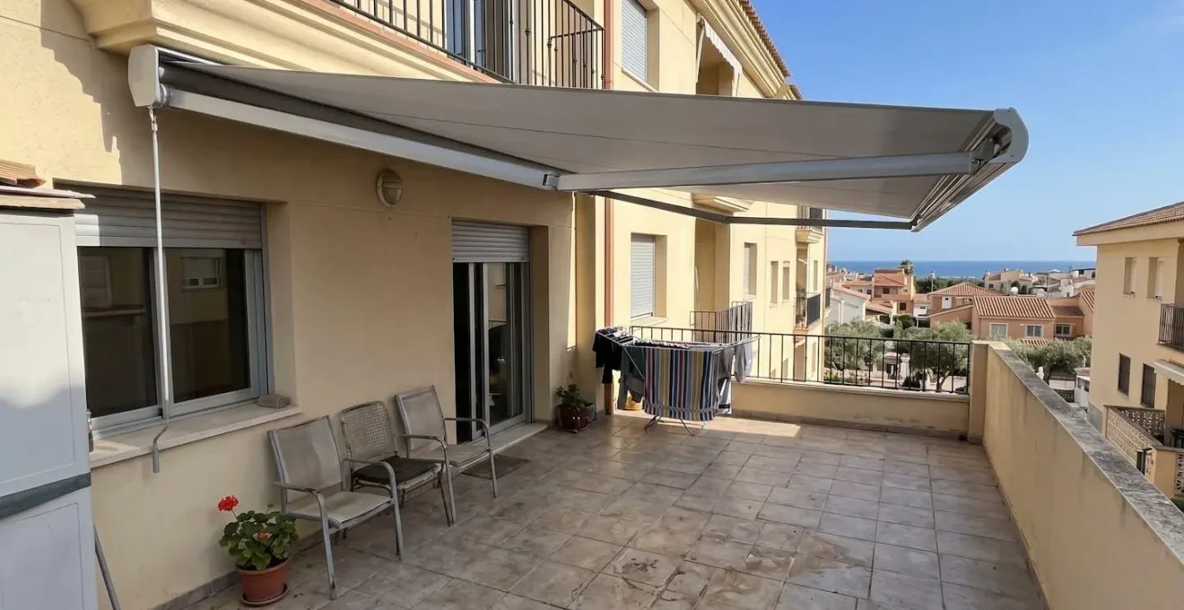 Toldo de aluminio extendido sobre terraza residencial con estructura del armazón visible en día soleado