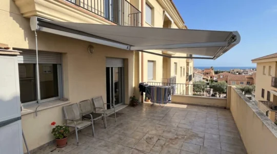 Toldo de aluminio extendido sobre terraza residencial con estructura del armazón visible en día soleado